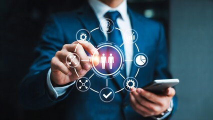 Businessman interacting with digital interface displaying icons and holding a smartphone 