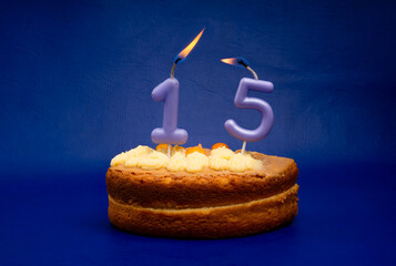 Birthday card with candle and cake: number 15 on a blue background.