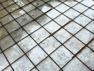 A grey and white tile floor with a metal grid pattern