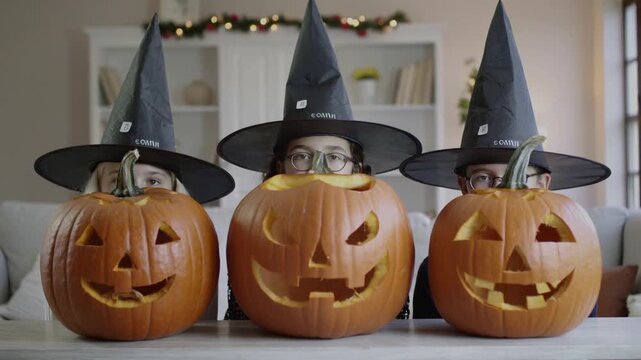 Tres niños ocultos detrás de  calabazas tallada para halloween