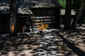 Furniture repair and maintenance, fixing rustic wood branch rocking chair outside classic log cabin, north rim Grand Canyon National Park, Arizona
