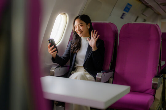 Woman on airplane using smartphone for video call - Powered by Adobe