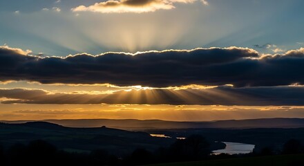 Golden Sun Rays Bursting Through Dramatic Sunset Clouds Over a Landscape.