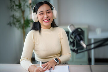 Asian woman smiling, podcasting and writing at desk