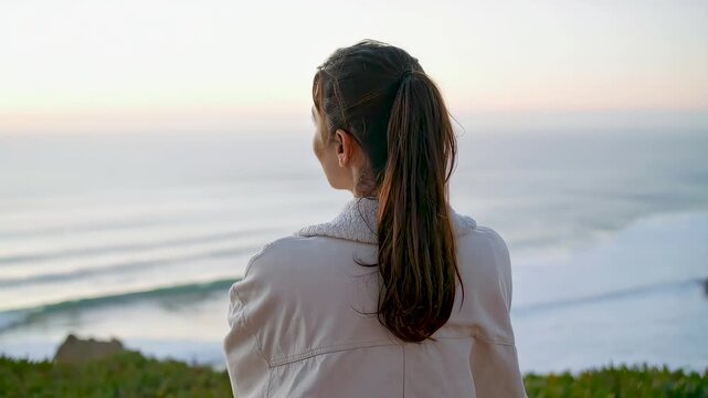 Mujer de espaldas contemplando el mar desde un acantilado