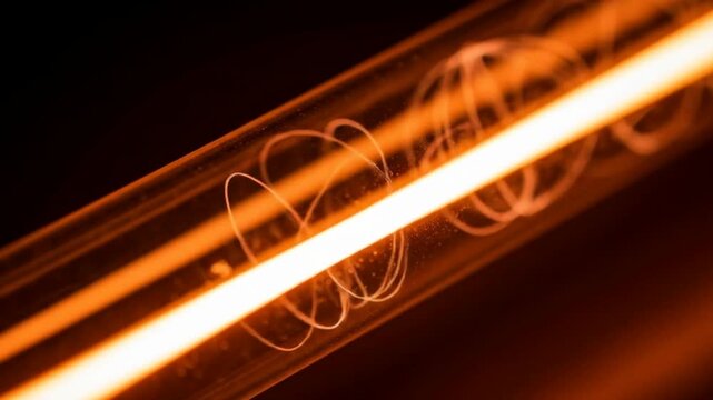 A macro photograph of a glowing orange incandescent filament with a spiral wire inside a glass tube.