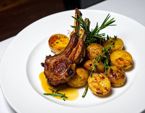 Stylized gourmet interpretation of Xai rostit, traditional Andorran roasted lamb with potatoes, plated in modern fine dining design.