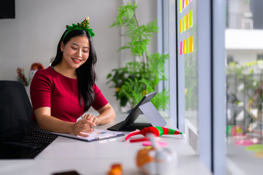 Happy Asian woman working in office during Christmas holiday