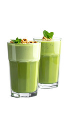 Two glasses of vibrant green smoothie, topped with chopped nuts and fresh basil