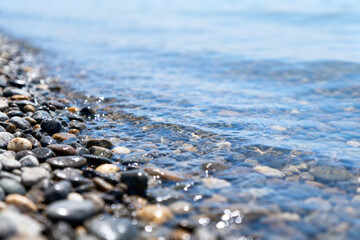 Close-up of pebbles along a shoreline with gentle waves lapping the beach