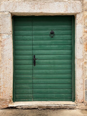 old wooden green door against stone frame on house exterior in Croatia