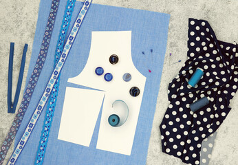 The process of sewing clothes using a pattern. Fabric, paper pattern, and sewing accessories on a table. Clothing design.