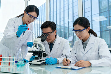 Scientists conducting laboratory research with microscope and test tubes