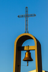 Obraz premium Church bell tower with cross against a blue sky. Symbol of faith, architecture, and religious tradition.