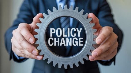 Business professional holding gear with "POLICY CHANGE" text, symbolizing strategic adaptation and transformation.