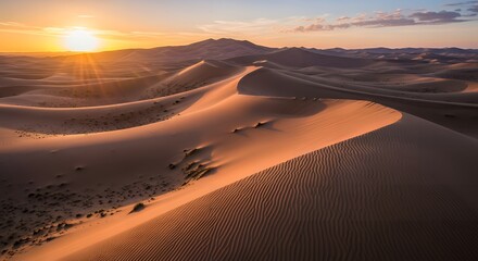 Golden sunset illuminates vast desert sand dunes creating a serene scene