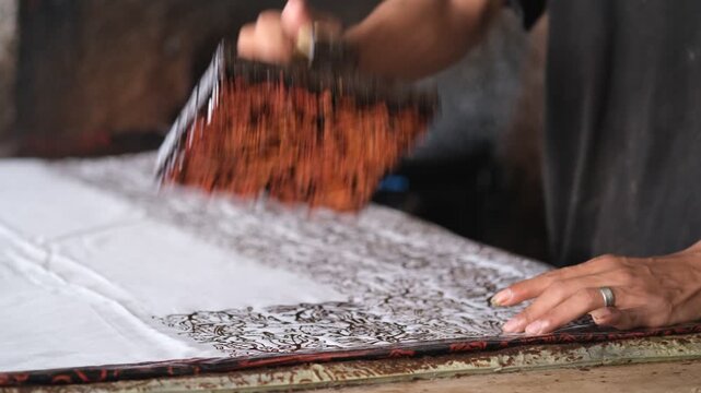 A worker at the Betawi batik factory is stamping batik patterns onto fabric using a metal plate that has been shaped into the design. Jakarta, Sept 20, 2025.
