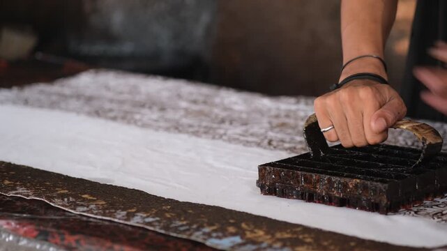 A worker at the Betawi batik factory is stamping batik patterns onto fabric using a metal plate that has been shaped into the design. Jakarta, Sept 20, 2025.