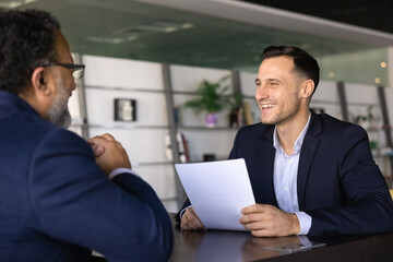 HR manager sit at table, hold CV, communicates with applicant