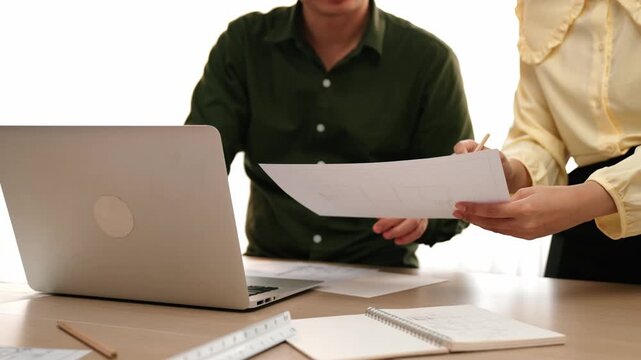 Architect and engineer compare hand writing draft with construction blueprint detail display in laptop for accurate design, measurement tool and plan on table at modern office. Closeup. Delineation.