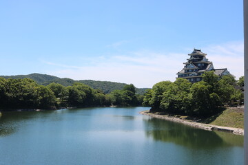 青空と緑に映える岡山城と川の美しい風景