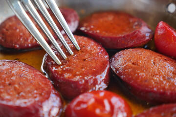 Sliced sausage cooked in oil with fresh peppers on a plate