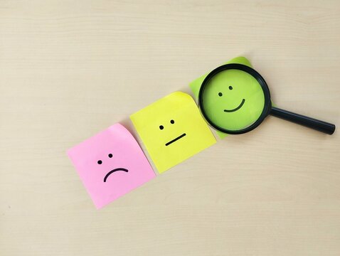 Not satisfied, neutral, and happy emoji on colorful sticky notes with wooden table background customer satisfaction concept. Flat lay 