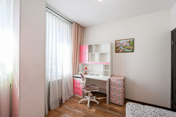 Bright room featuring a desk, chair, shelving unit and pink accents. Natural light filters through the window