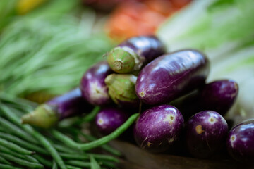 A vibrant, colorful display of fresh and organic eggplants surrounded by an assortment of various vegetables