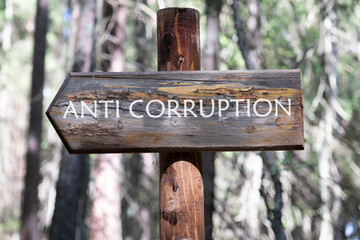 ANTI CORRUPTION text writing on the arrow from the board against the background of the forest
