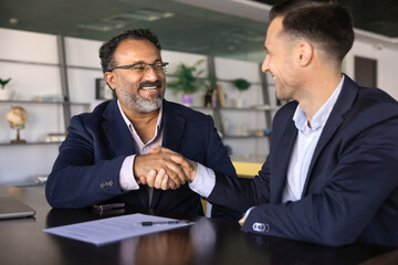 Indian older 45s businessman shaking hands with Hispanic business partner