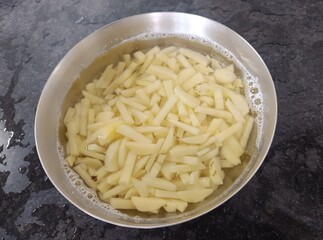The image shows raw, cut potatoes soaking in water, which is a common preparation step for making French fries. 
