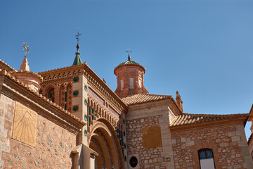 Mudejar tower of the Cathedral of Santa Maria de Mediavilla in Teruel with ornamental details and a blue sky in the background