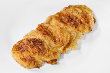 A golden, flaky Danish pastry with a crisp surface and soft, layered interior, baked to perfection with a rich buttery aroma.  croissant on a plate on white background.