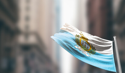 San Marino national flag waving on street. A beautiful with mast with blur buildings. San Marino...