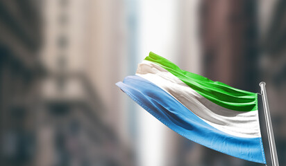 Sierra Leone national flag waving on street. A beautiful with mast with blur buildings. Sierra...
