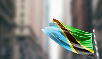 Tanzania national flag waving on street. A beautiful with mast with blur buildings. Tanzania...