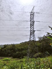 Outdoor Scenic View of Power Transmission Tower on Green Hillside Landscape