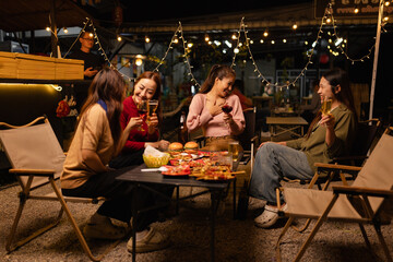 Happy Friends Celebrating Together at Night, Young Asian Group of Friends Having Fun and Toasting Drinks Outdoors, Enjoying a Celebration Concept.