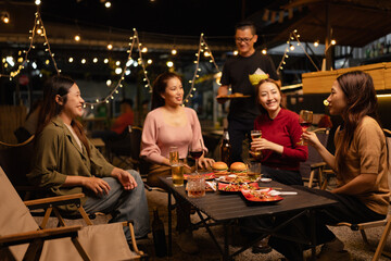 Happy Friends Celebrating Together at Night, Young Asian Group of Friends Having Fun and Toasting Drinks Outdoors, Enjoying a Celebration Concept.
