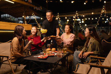 Happy Friends Celebrating Together at Night, Young Asian Group of Friends Having Fun and Toasting Drinks Outdoors, Enjoying a Celebration Concept.