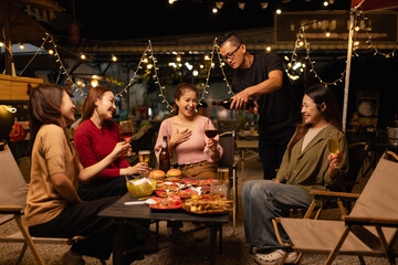Happy Friends Celebrating Together at Night, Young Asian Group of Friends Having Fun and Toasting Drinks Outdoors, Enjoying a Celebration Concept.