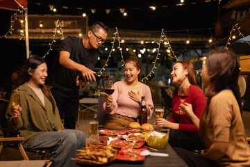 Happy Friends Celebrating Together at Night, Young Asian Group of Friends Having Fun and Toasting Drinks Outdoors, Enjoying a Celebration Concept.