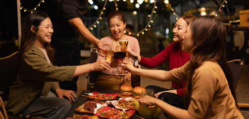 Happy Friends Celebrating Together at Night, Young Asian Group of Friends Having Fun and Toasting Drinks Outdoors, Enjoying a Celebration Concept.