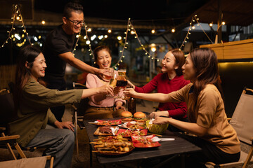 Happy Friends Celebrating Together at Night, Young Asian Group of Friends Having Fun and Toasting Drinks Outdoors, Enjoying a Celebration Concept.