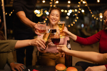 Happy Friends Celebrating Together at Night, Young Asian Group of Friends Having Fun and Toasting Drinks Outdoors, Enjoying a Celebration Concept.