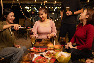 Happy Friends Celebrating Together at Night, Young Asian Group of Friends Having Fun and Toasting Drinks Outdoors, Enjoying a Celebration Concept.