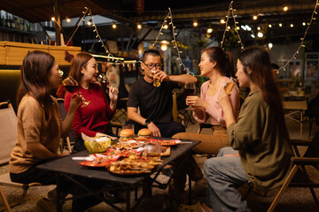 Happy Friends Celebrating Together at Night, Young Asian Group of Friends Having Fun and Toasting Drinks Outdoors, Enjoying a Celebration Concept.