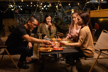 Happy Friends Celebrating Together at Night, Young Asian Group of Friends Having Fun and Toasting Drinks Outdoors, Enjoying a Celebration Concept.