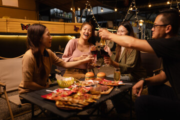 Happy Friends Celebrating Together at Night, Young Asian Group of Friends Having Fun and Toasting Drinks Outdoors, Enjoying a Celebration Concept.